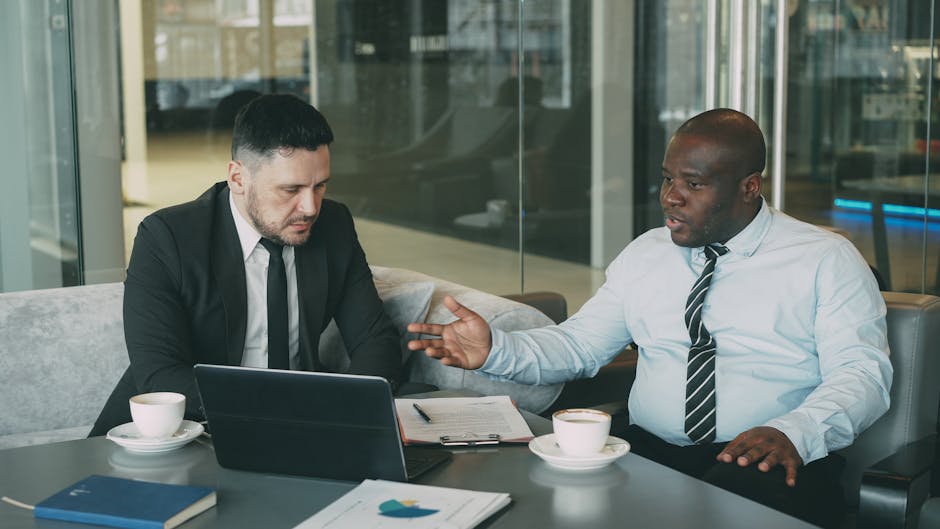 Two businessmen in a strategic discussion over coffee in a modern office setting.