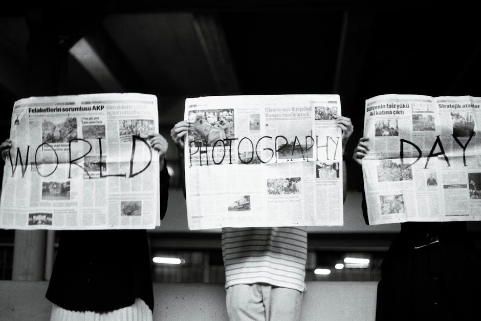Three people hold newspapers with 'World Photography Day' text, artistic vibe.